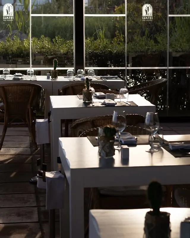 Tables framed by glass walls and greenery