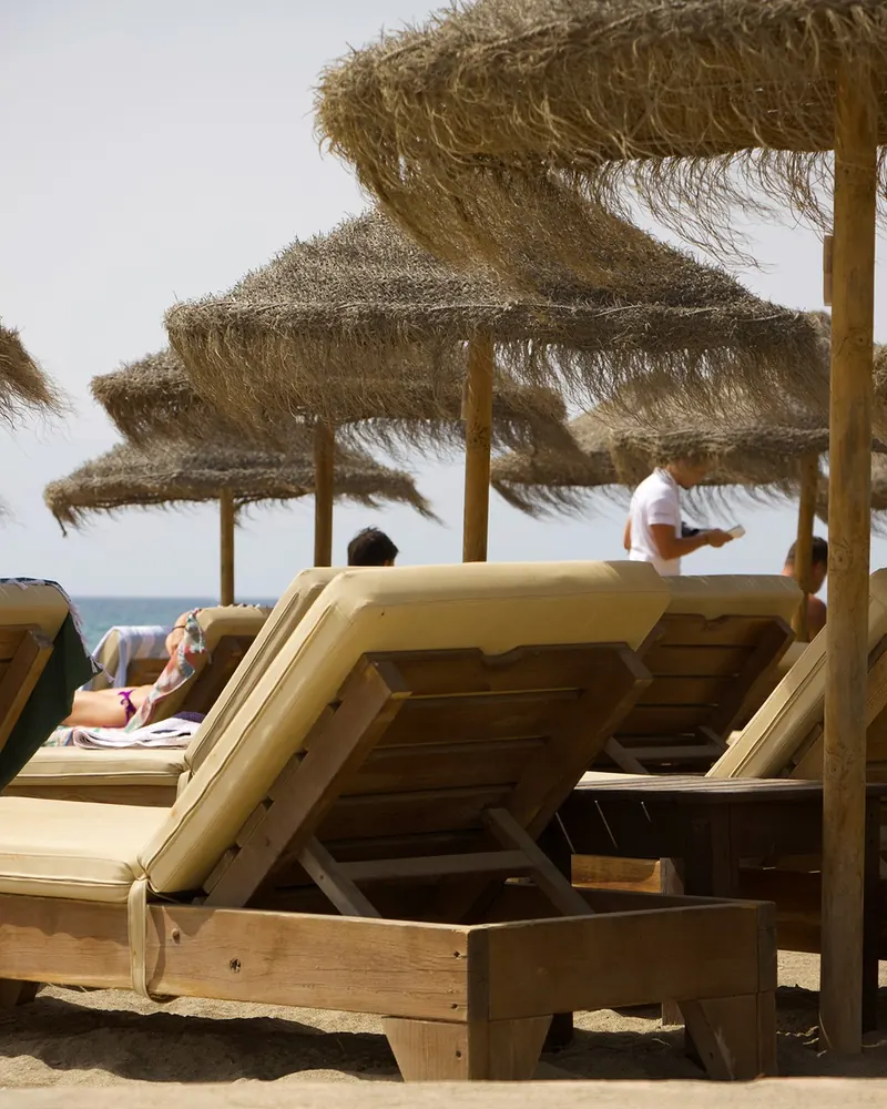 Wooden sun loungers and palm-leaf umbrellas on the beach
