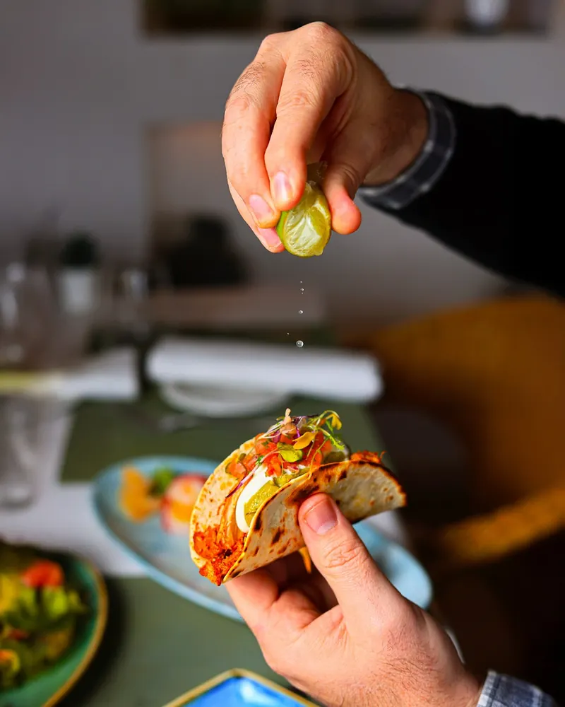 A chef squeezing lime over a taco