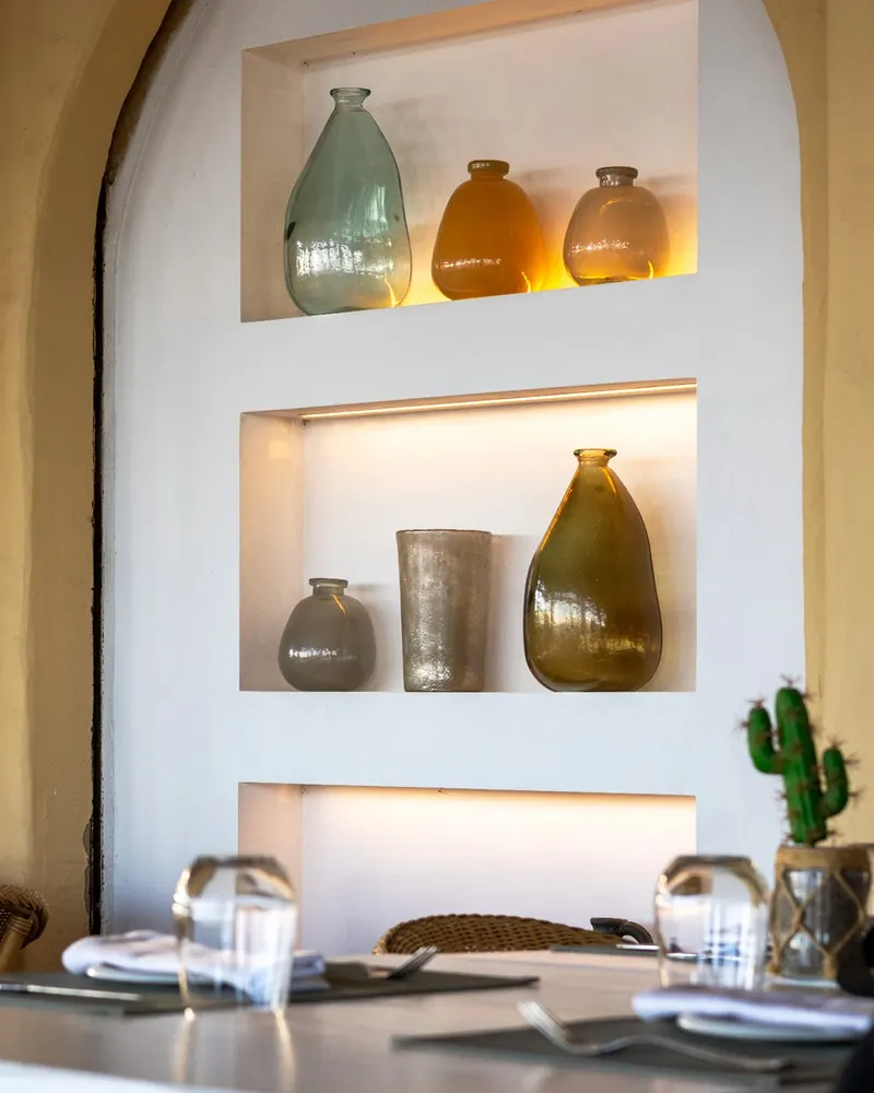 Whitewashed arched niches holding green and amber glass vases