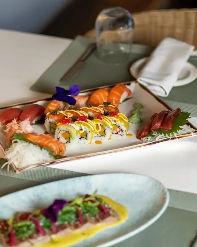 Sushi rolls and tuna tataki on a laid table